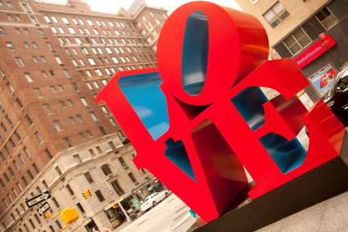 New York City, USA - May 02 2010: LOVE is a famous sculpture by american artist Robert Indiana. Located on 55th street and 6th Ave. Defocused buildings on the back.