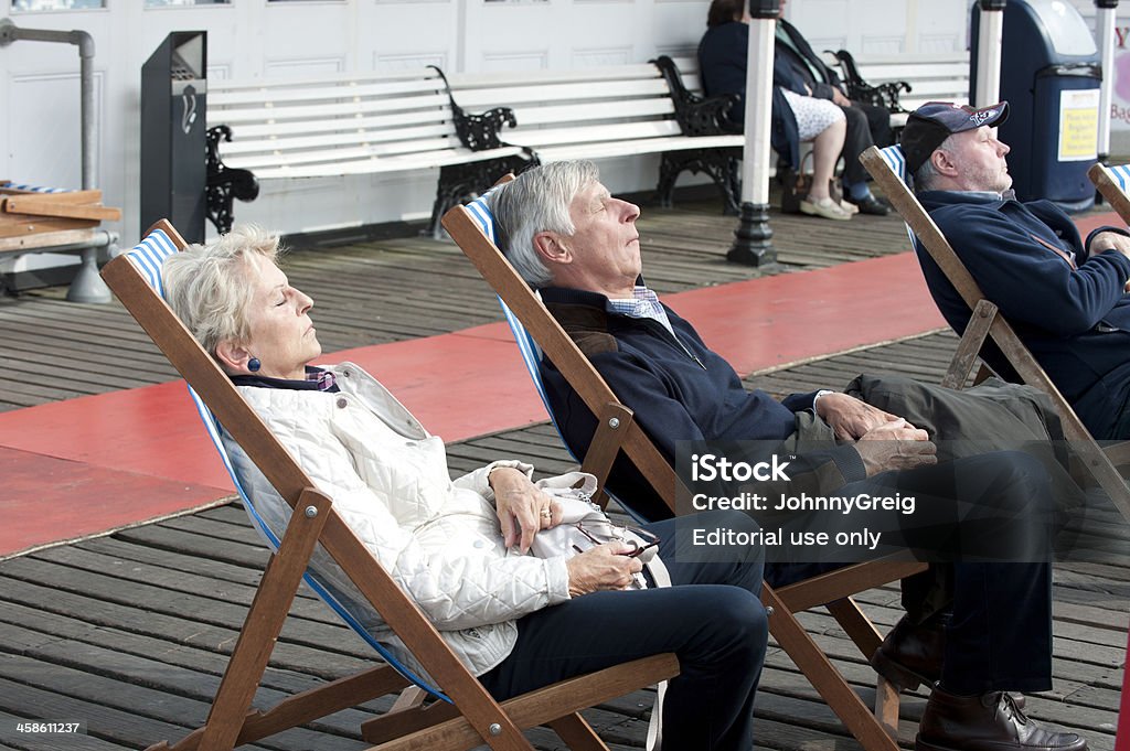 Anziani dormire in sedie a sdraio sul molo di Brighton - Foto stock royalty-free di Ambientazione esterna