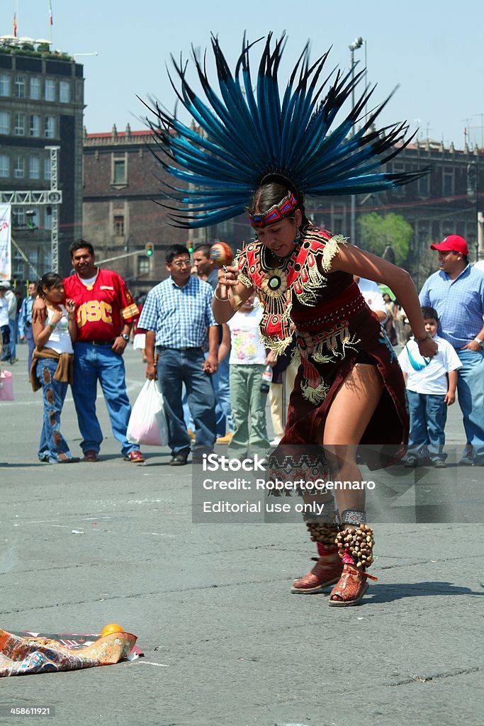 Aztec dancer Mexico City, Mexico - March 4, 2007: Plaza de la Constitution (Zocalo) at the Mexican capital city is the stage of political events and cultural performances. Here a woman dressed with Aztec clothes is performing a tribal dancing. A group of spectators is looking at her. Ceremonial Dancing Stock Photo