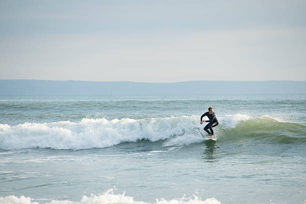 Man Surfing at Croyde Bay in Devon Croyde, England, UK - July 2, 2011: A man surfing at Croyde Bay in North Devon. Croyde Bay in Devon is part of the Heritage Coastline in North Devon and is a popular destination for surfers. croyde photos stock pictures, royalty-free photos & images