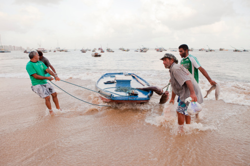 Fortaleza, Brazil - November 14, 2011: Fishermen are coming form fishing in early morning, they all trying to carry their boat to the beach of fishmarket