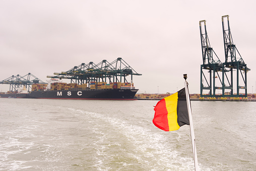 Antwerp, Belgium - June, 25 2011: View from a boat with Belgian flag  on the MSC (Mediterranean Shipping Company) cargo with cranes and containers docked at the MSC terminal in the Delwaide Dock in the Port of Antwerp. 