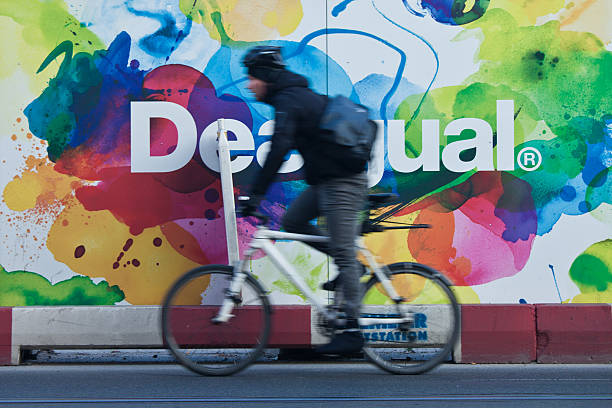 Cycling on the Streets of Berlin Berlin, Germnay - November 14, 2011: Young man cycling on the streets of Berlin and passing in front of a colourful an advertisment poster berlino stock pictures, royalty-free photos & images