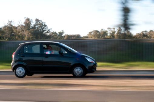 Cape Town, South Africa - March 15, 2011: Man driving with small vehicle towards Cape Town International Airport, talking on his mobile phone.