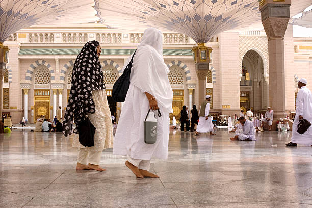 Medina, Saudi Arabia - April 15, 2011: Muslim pilgrims walking in the courtyard of Masjid al-Nabawi ( Prophet's Mosque ) after the noon prayer. As the final resting place of the Prophet Muhammad, it is considered the second holiest site in Islam by Muslims (the first being the Masjid al-Haram in Mecca).