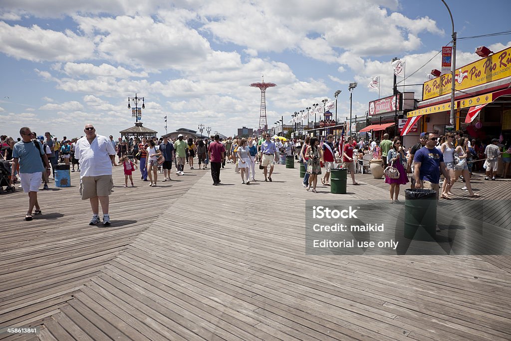 Fourth of July at Coney Island "New York, USA - July 4, 2009: A group of people walk on the sidewalk to the beach at Coney Island the fourth of July. Coney Island is a popular summertime retreat for New Yorkers." Adult Stock Photo