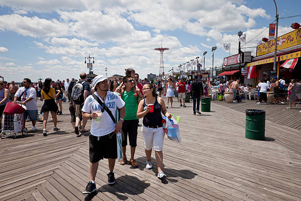 New York City, New York, USA - July 10, 2015: Sunset view of historic Coney Island boardwalk in Brooklyn with amusement park rides and people visible.