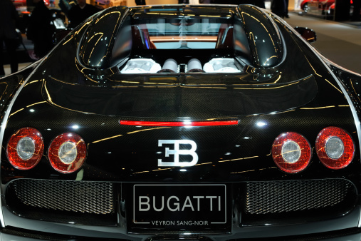 Amsterdam, The Netherlands - April 12, 2011: Black Bugatti Veyron Sang Noir  on display at the 2011 Amsterdam AutoRAI motor show. People in the background are looking at the cars. The 2011 Amsterdam motor show was running from April 12 until April 23, in the RAI event center in Amsterdam, The Netherlands.
