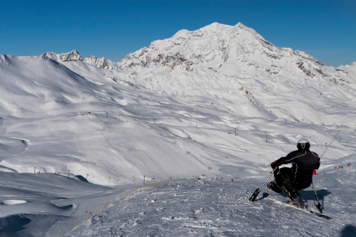 Tignes, France - December 9, 2009: adult disabled man on the specjal ski on a sunny day with the snow covered Alps seen below in the background. Tignes is a popular France ski resort.