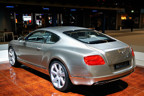 Amsterdam, The Netherlands - April 12, 2011: Gray Bentley Continental GT coupe on display at the 2011 Amsterdam Motor Show. People are looking at the cars in the background. The 2011 Amsterdam motor show was running from April 12 until April 23, in the RAI event center in Amsterdam, The Netherlands.