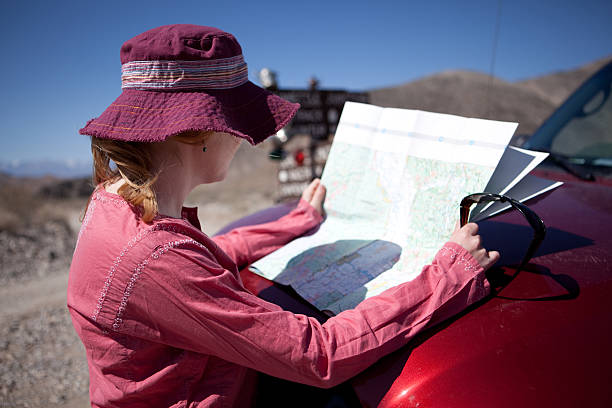 Young woman looking at map in Death Valley National Park Death Valley National Park, California - March 20,2009 teakettle junction stock pictures, royalty-free photos & images