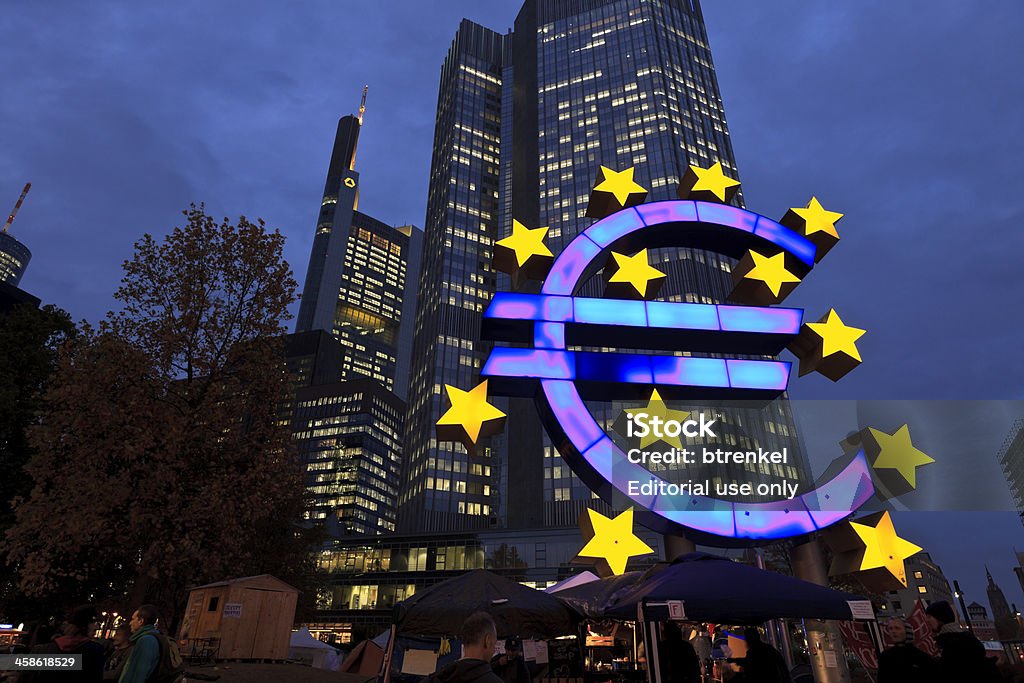 Occupy Movement &amp; European Central Bank at dusk Frankfurt/Main, Germany - November 2, 2011: The European Central Bank at dusk; has since summer 2011 become the 'symbol' of the economic woes surrounding the Euro currency and the endless meetings to stabilize economics participating in the Euro who are heavily indebted. Below the Euro Symbol, the Occupy movement has installed a camp site to demonstrate against the ECB and it's policies. Accidents and Disasters Stock Photo