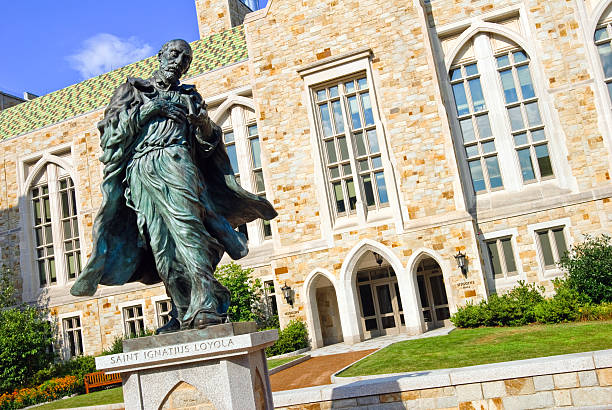 Saint Ignatius Loyola statue and Higgins Hall at Boston College Chestnut Hill, United States - August 6, 2010: Saint Ignatius Loyola statue in front of Higgins Hall at Boston College, sculpted by Pablo Eduardo. boston college campus stock pictures, royalty-free photos & images