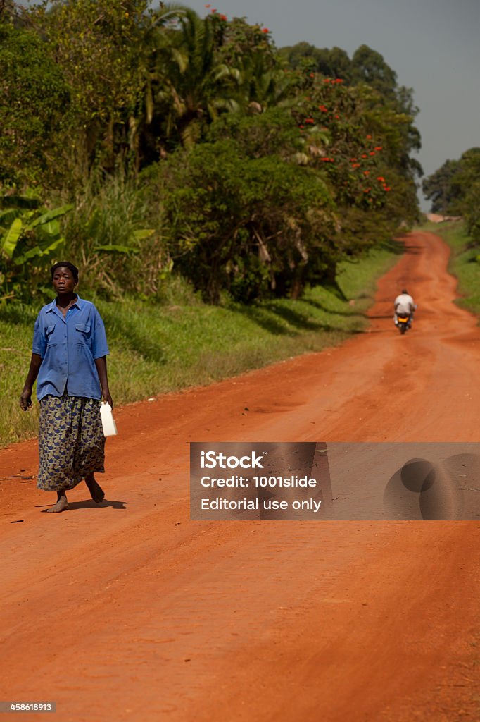 Proud African Woman walking on the village road Hoima, Uganda - November 23, 2011: Proud African Woman walking on the village road under the strong sunlight against the camera close Hoima city, Uganda, Africa Adult Stock Photo