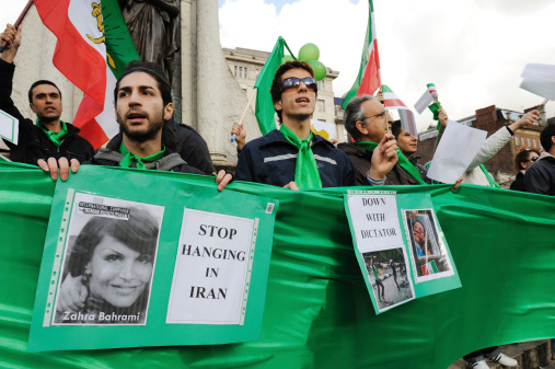 Manchester, England - February 12, 2011:Iranian protestors gather in the Piccadilly Gardens area of Manchester, waving flags and holding banners to protest against the ongoing hangings of Iranian citizens and the dictatorship of Mahmoud Ahmadinejad the sixth and current President of the Islamic Republic of Iran.