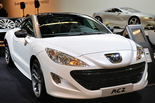 Amsterdam, The Netherlands - April 12, 2011: White Peugeot RCZ on display at the 2011 Amsterdam Motor Show. Peugeot SR1 on display in the background. The 2011 Amsterdam motor show was running from April 12 until April 23, in the RAI event center in Amsterdam, The Netherlands.