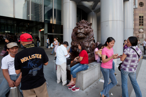 Hong Kong, China - August 7, 2011: Filipino domestic helpers gathered during Sunday at the Lion statues in front of the HSBC headquarters building in the Central District of Hong Kong. The Filipinos are challenging an immigration law that bars foreign helpers who have lived in Hong Kong for more than seven years from gaining permanent residency.
