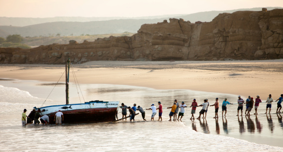 Lobitos, Peru - March 14, 2010: Fishermen hauling in their boat. In the small community of Lobitos Peru, the fishermen have not abandoned their community traditions, but instead all work together one day a month to clean and repair the boats of whoever is most in need.