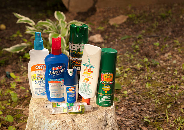 Insect Repellent Lotions and Bug Sprays Phoenix, Arizona, United States - June 21, 2011: A collection of bug sprays and lotions are displayed on a tree stump.  Insect repellants are important to ourdoorsmen and to those trying to avoid contracting mosquite-borne diseases such as West Nile Virus and encephalitis. DEET stock pictures, royalty-free photos & images