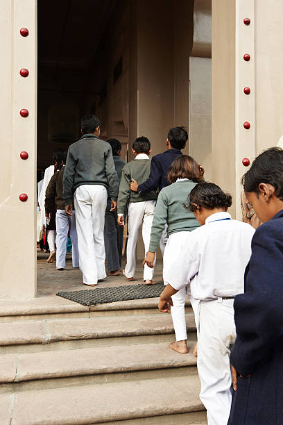 Varanasi, India - November 28, 2010: A line of schoolchildren walking barefoot up the steps to visit an Indian temple in Varanasi.