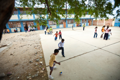 Lobitos, Peru - March 11, 2010: A group of Peruvian school kids plays soccer during their lunch break on a cement court in the courtyard of their school.