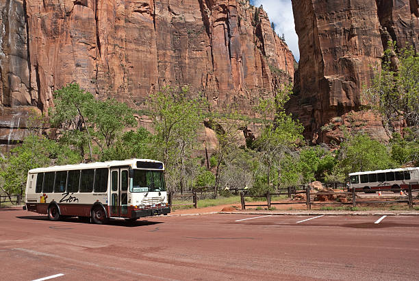 Driver Waits Outside Her Bus as Two Bikers Pass Zion National Park, Utah, USA - May 10, 2011: A system of free shuttle buses helps to limit visitor impact in the national park. jeff goulden environmental conservation stock pictures, royalty-free photos & images