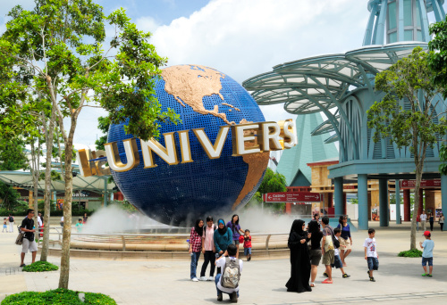 Singapore City, Singapore - March 28, 2011: Universal Studios. The image shows the famous Universal Studios Globe outside of the entrance to the theme park in Singapore. Many visitors of Asian ethnicity can be seen posing for photos around globe. The park was completed on Sentosa Island in 2010 and the official opening ceremony took place in May 2011. Universal Studios is a major global brand and the Singapore theme park is their first in SE Asia,