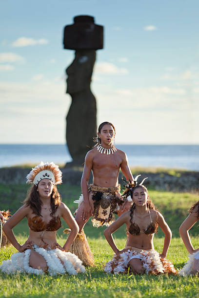 Hanga Roa, Chile - Abril 18, 2010: Group of three young people in traditional clothing dancing and singing in front of the Ahu Tahai on the Easter Island, Chile.