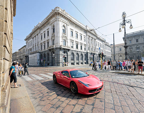 Milan, Italy - October 1, 2011: A man driving a Ferrari 458 Italia past pedestrians on Piazza della Scala in central Milan.  Ferrari introduced the 458 Italia model in 2009.