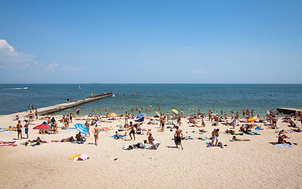 Odessa, Ukraine - July, 12th 2011: Scene at Arcadia beach during peak tourist season. Around 100 people, all ages - are seen on this secluded part of the beach and in the water. The beach is located by the Black sea.