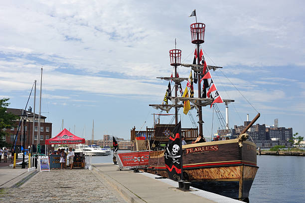 Baltimore, Maryland, USA - July 30, 2011. Ticketing booth and ship of Urban Pirates at waterfront of Fell\\'s Point. Fell\\'s Point is a historic neighborhood located on the harbor in Baltimore, famous for its maritime past and variety of shops, restaurants and pubs/bars. It is listed on the National Register of Historic Districts in US.