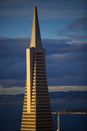 San Francisco, California - June 1, 2011: The Transamerica Pyramid Building glows in the golden light of the setting sun. Berkeley and Oakland can be seen across the San Francisco Bay in the background.