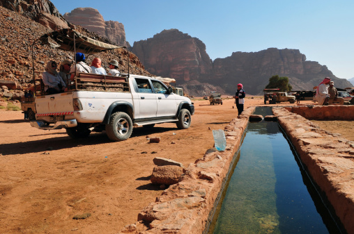 Wadi Rum, Jordan - November 14, 2010:Tourists and Bedouins stop at a spring in Wadi Rum, a protected area covering 720 square kilometers of dramatic desert wilderness in the south of Jordan. Huge mountains of sandstone and granite reach heights of 1700 meters and more. Much of the 1962 film Lawrence of Arabia, winner of seven Academy Awards including Best Cinematography, was filmed here.