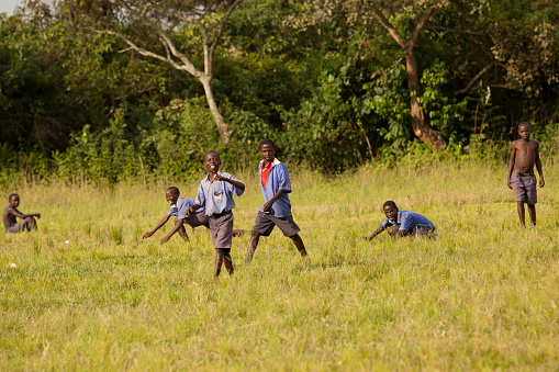 Hoima, Uganda - November 18, 2011: African kids - Groups of children different age are running and playing against the camera on the grasses at small village.