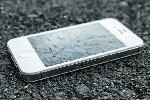 St. Gallen, Switzerland - May 11, 2012: white iPhone 4s with broken display laying on asphalt. The iPhone is a smartphone designed by Apple. The iPhone 4s is the latest on market.