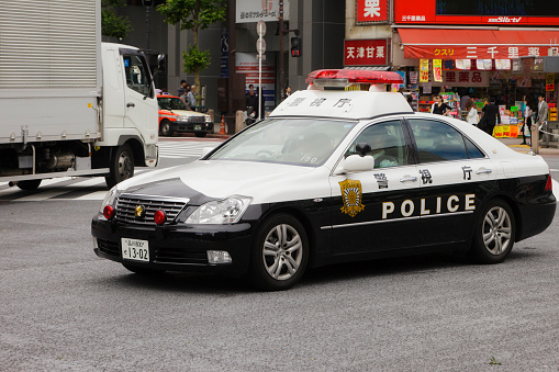 Tokyo, Japan - May 30, 2011: A police car from the Tokyo Metropolitan Police Department crosses the intersection at the Shibuya Crossing in front of the Shibuya Station Hachiko exit in the Shibuya Ward of Tokyo.