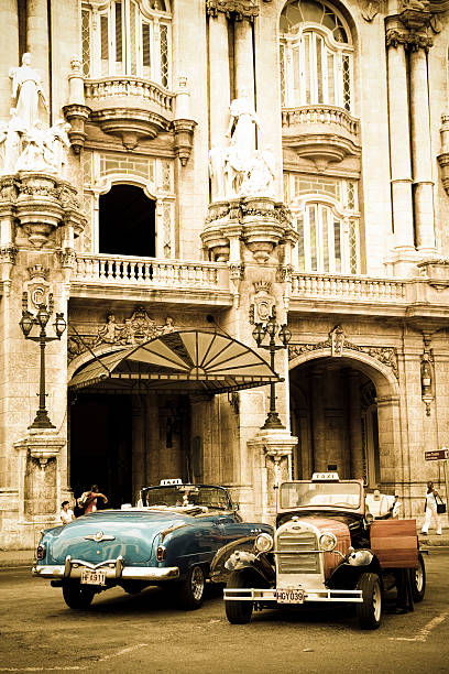 Two well-preserved old cars in Havana Vieja "Havana, Cuba- September 7, 2011: Two well-preserved old cars, Cadillac Series 62 Convertible 1952 and Ford A 1930, now taxis, in front of the hotel Telegraph, Havana Vieja." 1952 1952 stock pictures, royalty-free photos & images