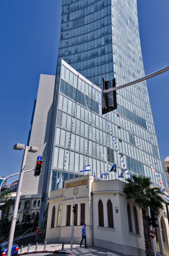 Tel Aviv, Israel - April 20, 2012: Tel Aviv is a beautiful city that contrasts the architecture of a modern city with that of a rich historical past. This street corner in Tel Aviv shows a modern day building adjacent to a structure from the early days of Israels birth.