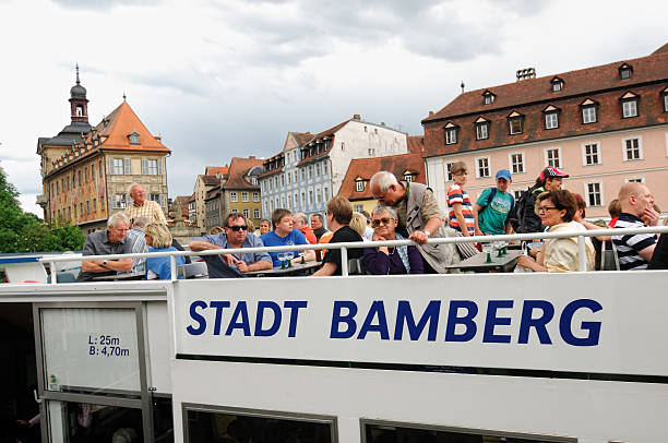 Bamberg, Germany - May 19, 2011: Tourist enjoying a city cruise on the River Regnitz through the historic Old Town of Bamberg with the famous Old Townhall (Altes Rathaus) in the background. Bamberg is located in Upper Franconia/Bavaria, Germany. The Old Town of Bamberg is listed as UNESCO World Heritage. 