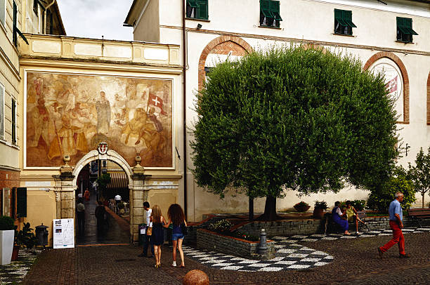Spotorno, Italy - july 23, 2011: Ancient gateway to the old town of Spotorno, surrounded by medieval walls. Some people come into the town, while some people are sitting on the bench