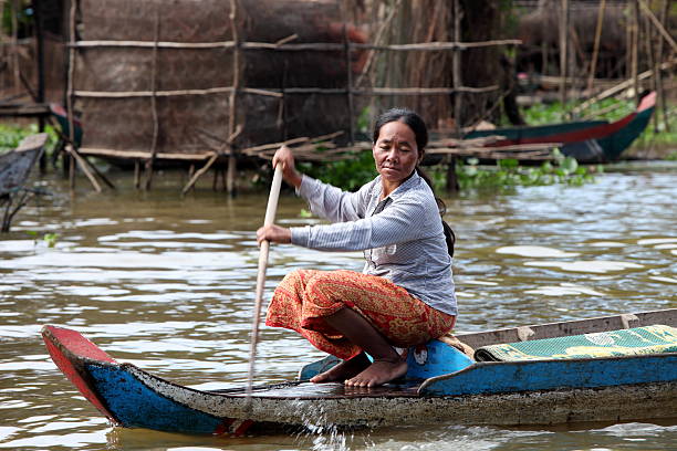 Kampong, Siem Reap, Cambodia 9 December 2012: A woman floating on a boat in the village built on the Tonle Sap lake.  People living on the water in the city of Siem Reap, Cambodia 09/12/2012