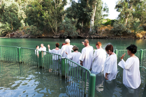 Yardenit, Israel - October 11, 2010: A view at the baptismal place at the Jordan river in Israel.The river\\'s water eventually flows into the Dead Sea located more than 100KM to the south of this location.This site is believed by some traditions to be the actual site where Jesus was baptized by John the Baptist.Many Christian pilgrims stop at this site and perform baptism ceremonies, normally in small groups and accompanied by the group\\'s pastor.