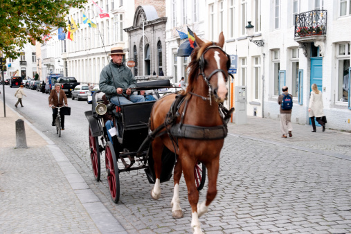 Brugge, Belgium - September 11, 2007: A horse drawn carriage with a driver and tourists passing through the streets of central Brugge, Belgium