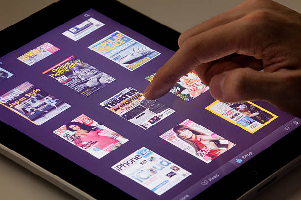 à l'aide d'une tablette en lisant un magazine - ipad apple computers digital tablet editorial photos et images de collection