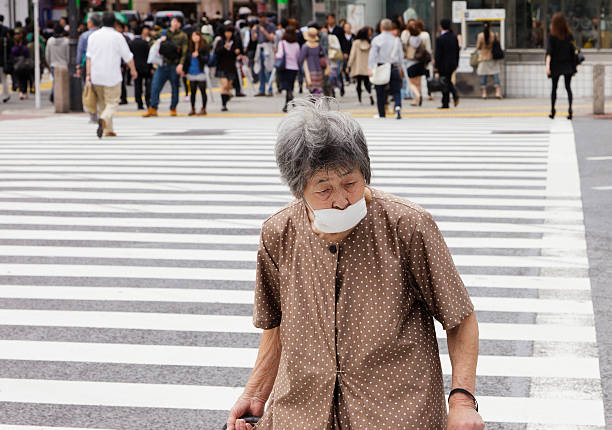 Tokyo, Japan - May 30, 2011: An elderly woman crosses the street at the pedestrian crosswalk in front of the Shibuya Station Hachiko exit in the Shibuya Ward of Tokyo.