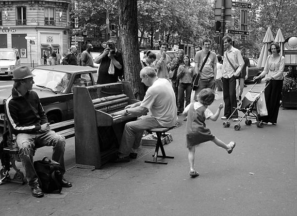 Paris, France. May 29,2005. A little girl dances while a man plays a piano on a sidewalk in Paris, France. A crowd of onlookers has gathered.