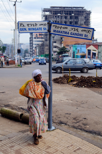 Addis Ababa, Ethiopia - July 30, 2010: A woman walks past a street sign marking the intersection of General Wingate and Mahatma Gandhi streets in the Ethiopian capital city of Addis Ababa