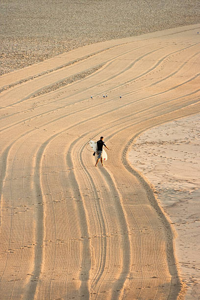 Man Going to Surf, Bondi Beach, Australia Sydney, Australia - March 7, 2010: Young man walking along bondi beach and holding his board is going going to surf at early morning. bondi beach sunrise stock pictures, royalty-free photos & images
