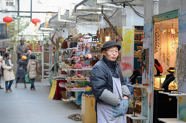 Men and women shopping on a street on a winter day in Wuhan, viewed through a narrow hutong alley