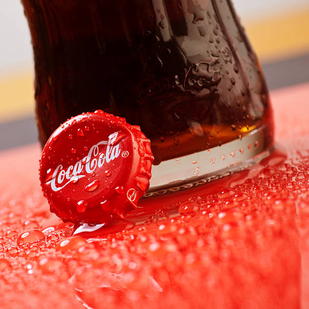 Coca Cola bottle cap on red and wet surface stock photo